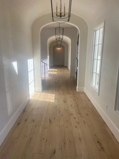 Sunlit hallway with wooden floors and arched ceilings.