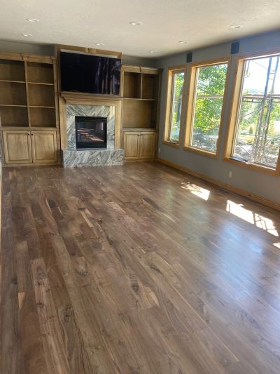 Empty living room with wooden floors, built-in shelves, and large windows.
