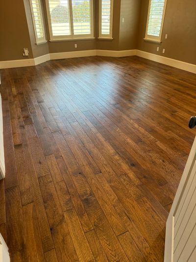Empty room with polished wooden flooring and bay windows.
