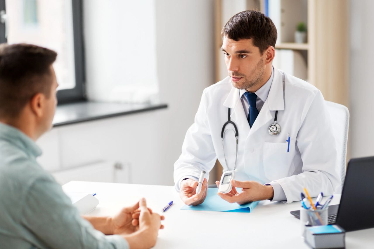 doctor with glucometer and insulin pen device talking to male patient at medical office who wants a nexus letter