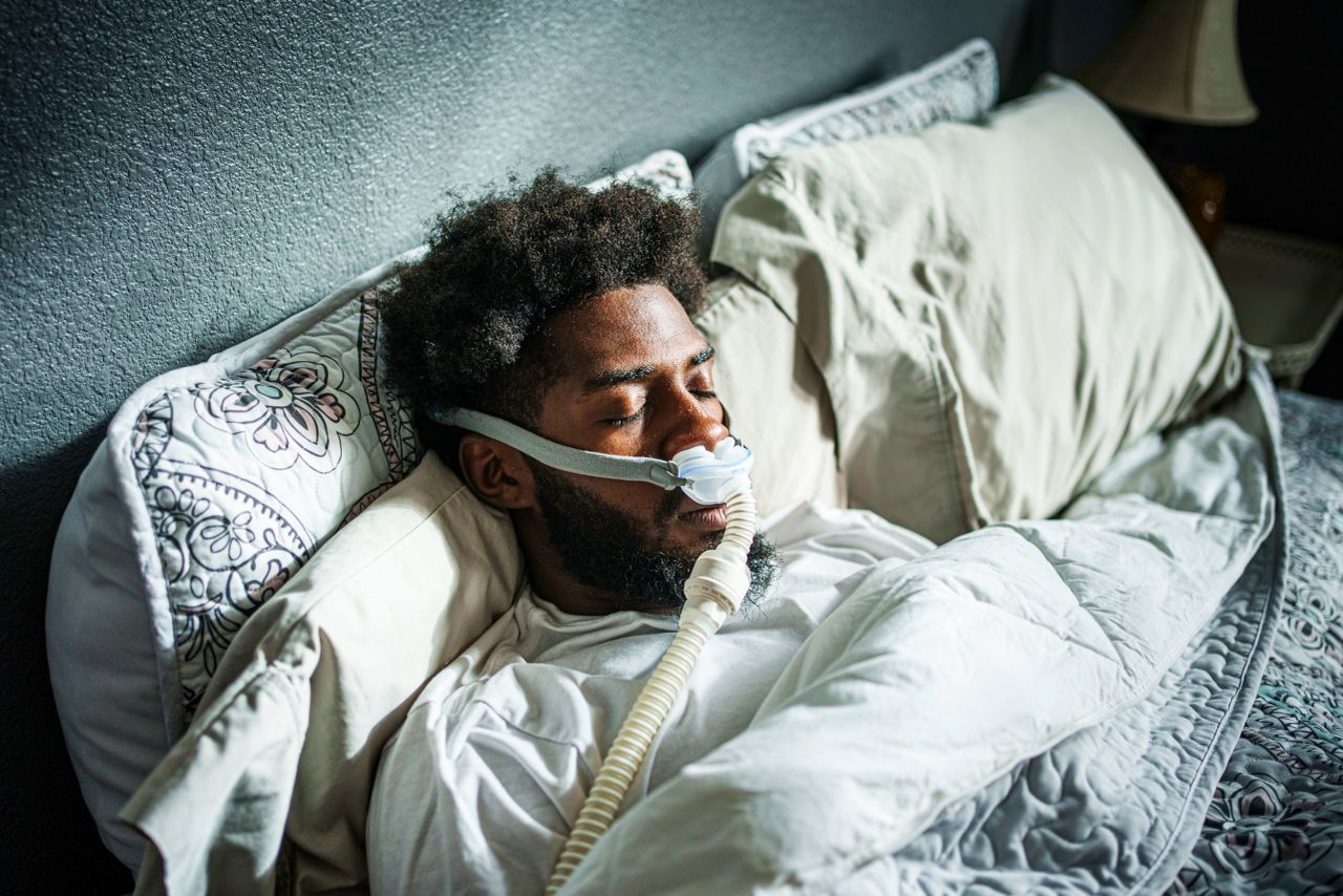 Man lying awake in bed at night, representing sleep paralysis episodes linked to obstructive sleep apnea.