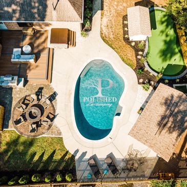 Birdseye view of putting green, firepit with patio, ourdoor kitchen, deck, and jacuzzi.