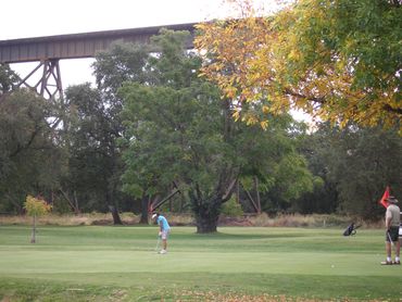 Golfers at Lake Redding Golf Course with Train Trestle in background