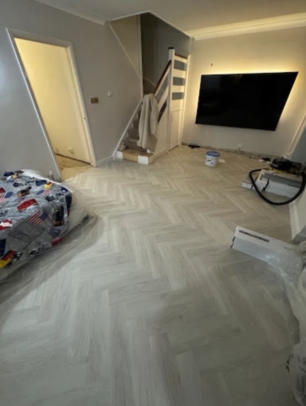 Living room with herringbone patterned flooring and a mounted TV.