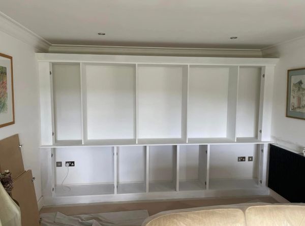 Empty white built-in shelves in a living room under construction.