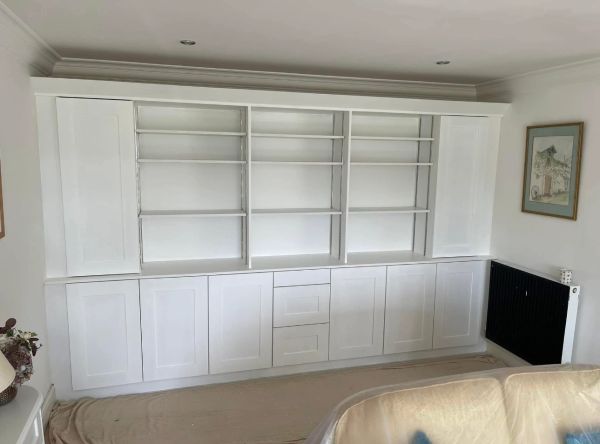 White built-in shelving unit with closed cabinets and open shelves in a living room.