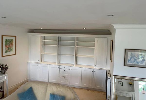 White built-in shelves and cabinets in a living room setup.