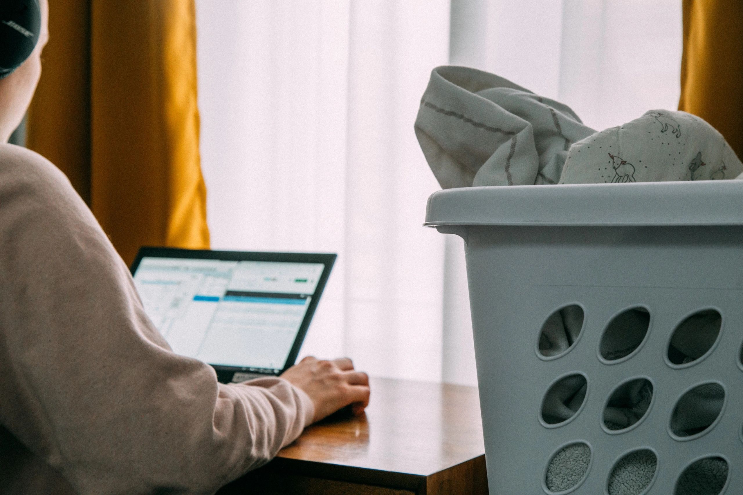 Building resident on laptop next to basket of laundry.