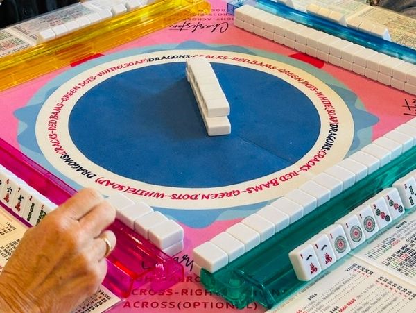 Mahjong game in progress with players arranging tiles.