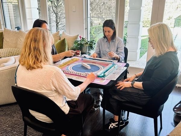 Four women playing a board game at a table indoors.