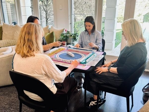 Four women playing a board game at a table indoors.