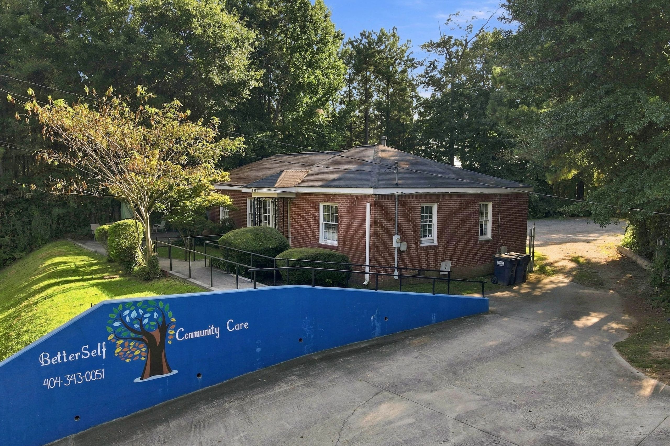 Brick building surrounded by trees with a blue community care wall.