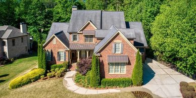Elegant two-story brick house surrounded by greenery and a spacious driveway.