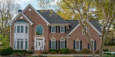 Large two-story brick house with white trim and black shutters.