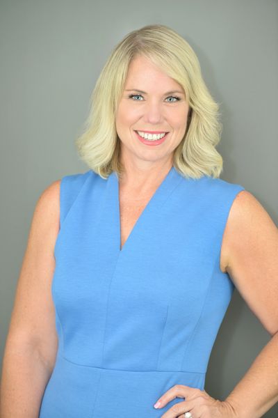Smiling woman in a blue sleeveless dress.