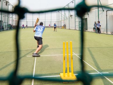 Players engaged in a cricket game on an outdoor pitch.