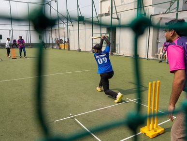 Kids playing cricket on an outdoor field during a sunny day.