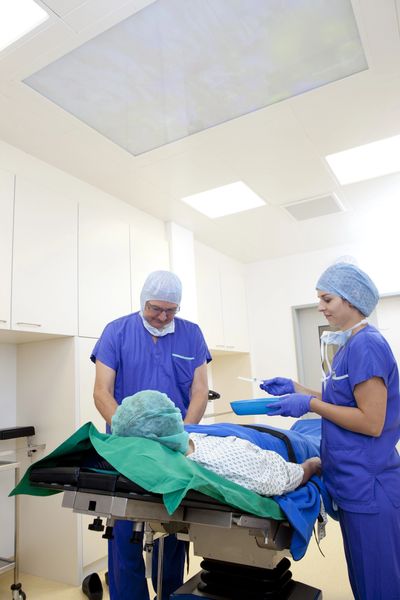 Medical team preparing patient for surgery in a sterile operating room.
