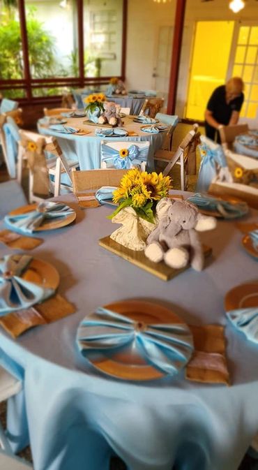 Blue-themed tables with sunflower centerpieces and elephant plush toys.