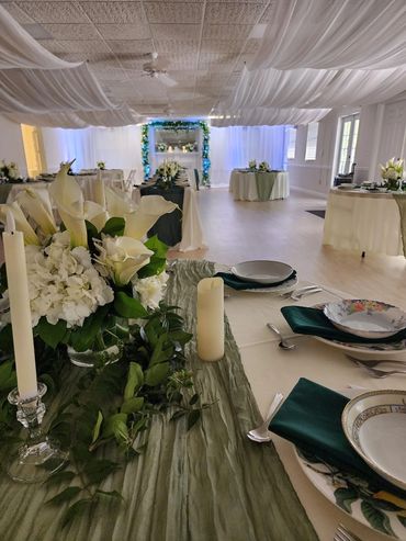 Elegant wedding reception with white flowers and green accents.