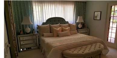 Drapes over window with a bed covered in pillows