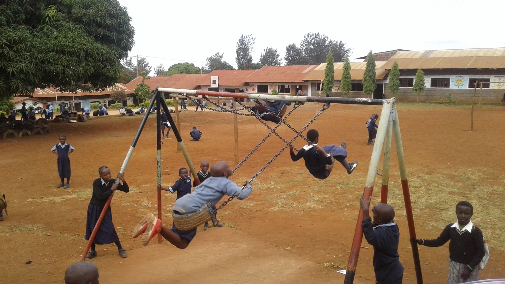 Chera Mission School, Kenya. Primary school aged children at play on swings in the school yard.