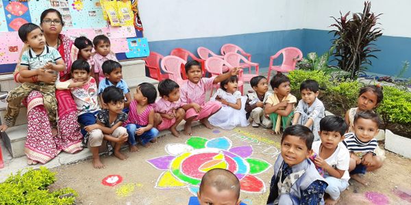 Pre school children in Gujarat, India sitting in a circle, listening to a story from their teacher. 