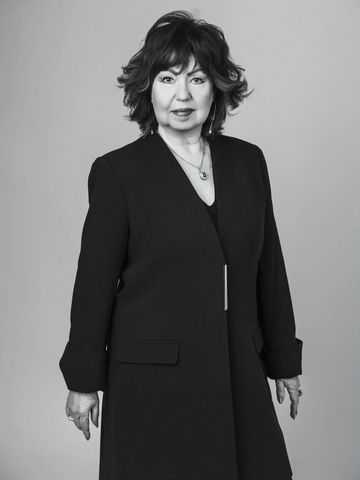 Confident woman in a black coat posing for a portrait.