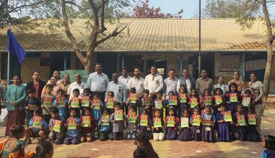 Group photo of schoolchildren and teachers holding certificates outside a school building.