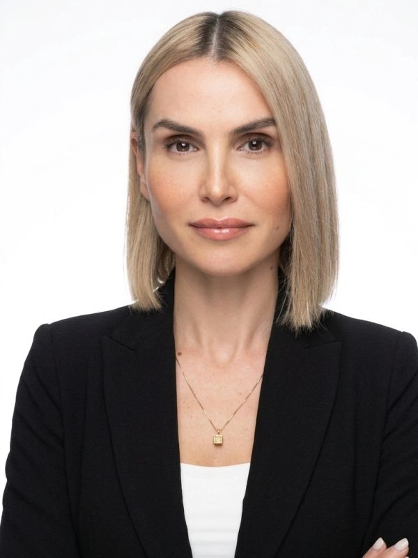 Professional woman with blonde hair wearing a black blazer and gold necklace.
