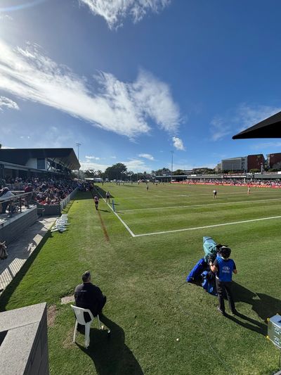 A sunny day at a sports field with spectators and players.