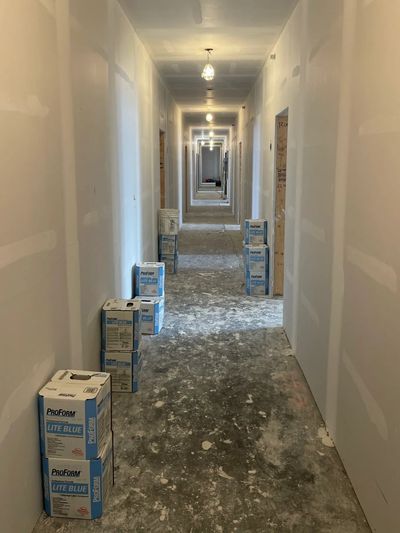 hallway with drywall and taping done and boxes of drywall mud