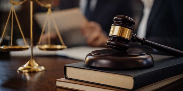 Judge's gavel on books with scales of justice in background.