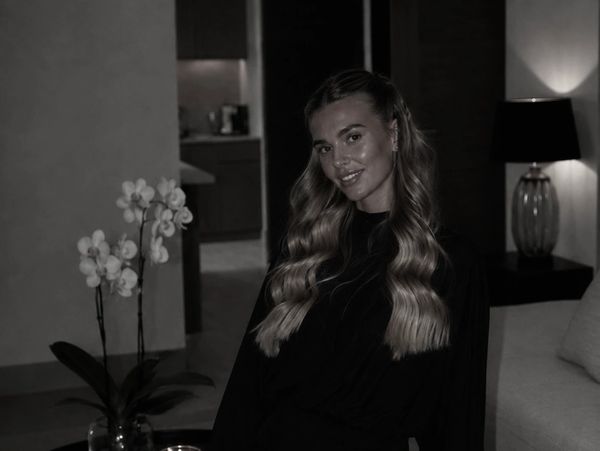 Young woman with long hair smiling indoors.