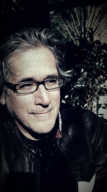 Man with glasses in leather jacket in sunlight.