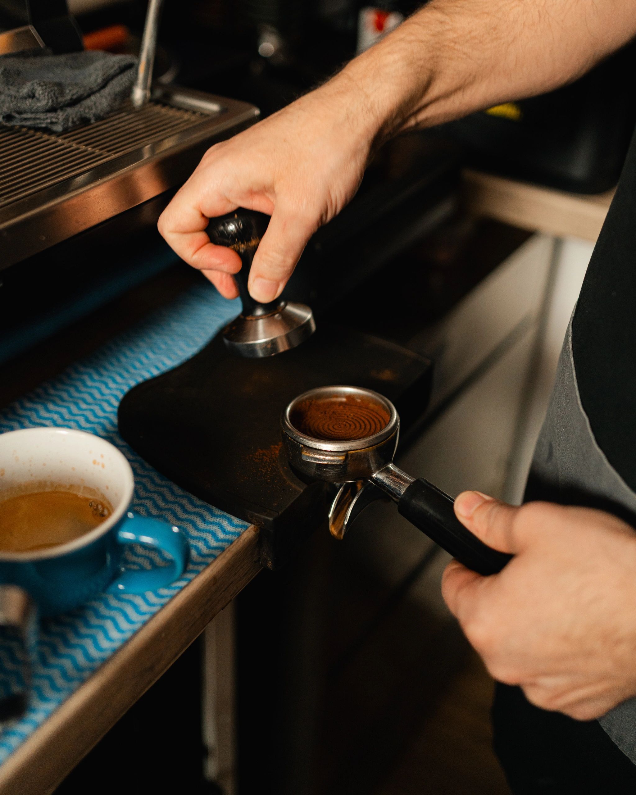A person tamping coffee grounds in a portafilter for espresso.