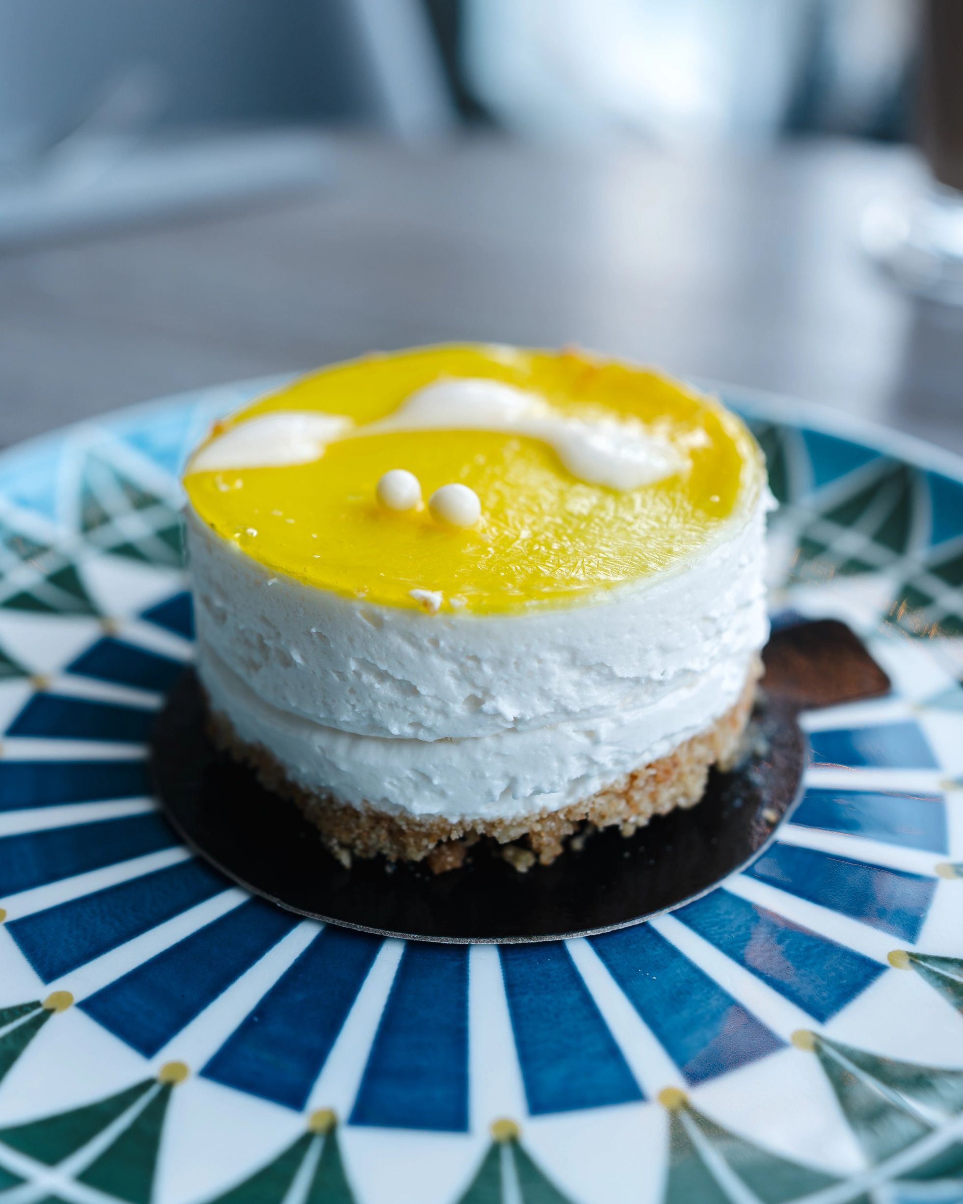 Close-up of a layered lemon mousse cake on a patterned plate.