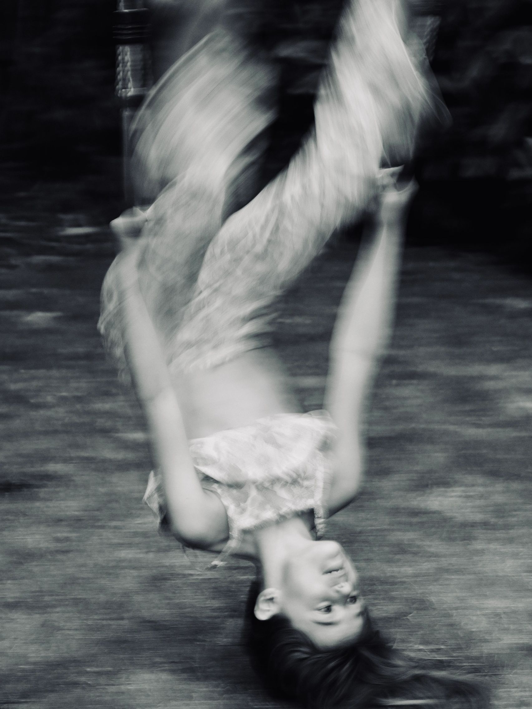 A girl upside down on a swing with blurry effects.