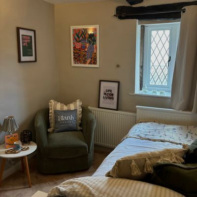 Cozy corner with armchair, bed, and framed art.