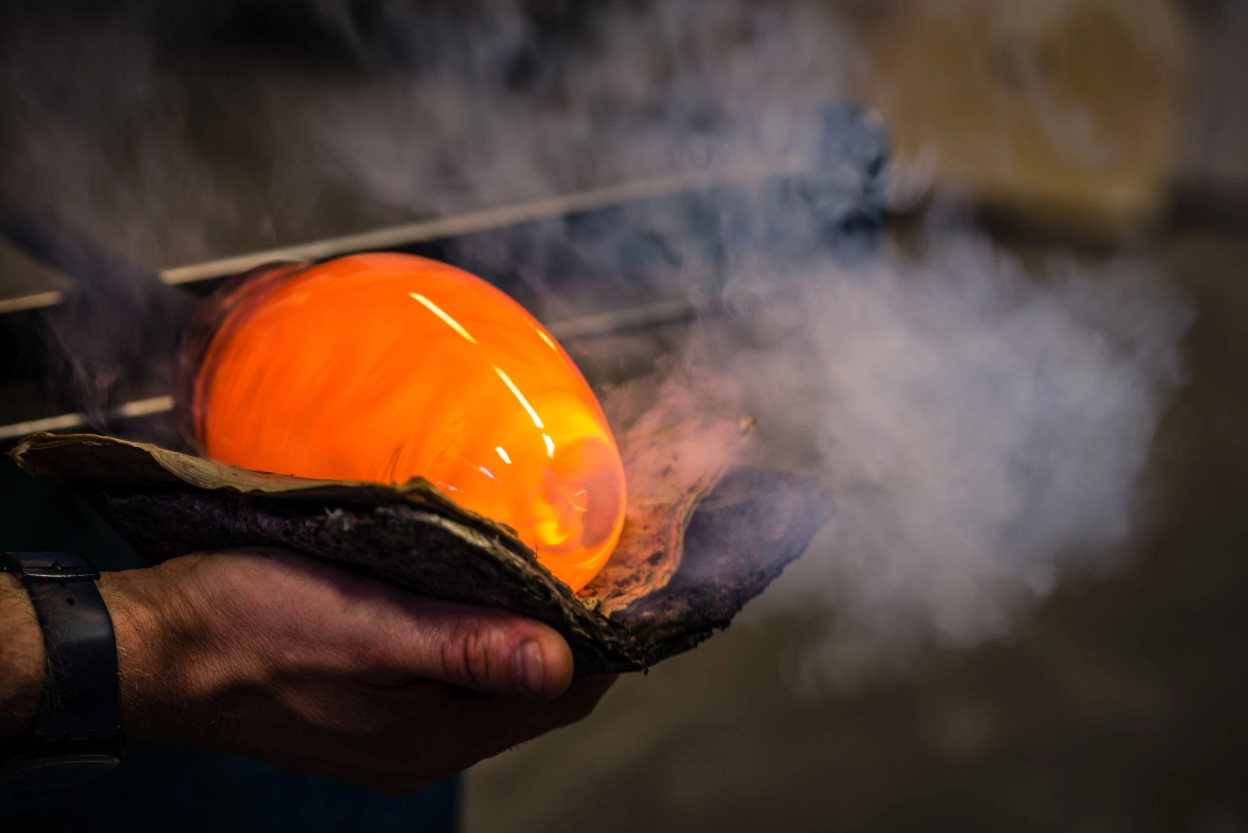 Glassblower shaping a molten gather on the pipe at Phoenix Glass Center