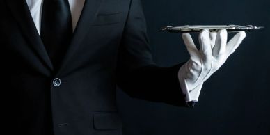A waiter in formal attire holding a polished serving tray.