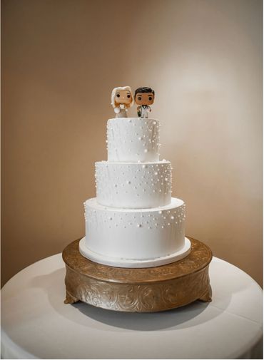 Three-tier white wedding cake with bride and groom toppers.