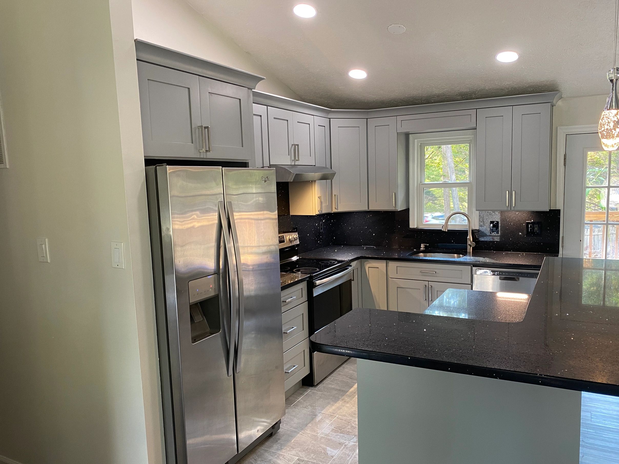 Beautiful kitchen, gray cabinets , black quartz , gray tile floor .