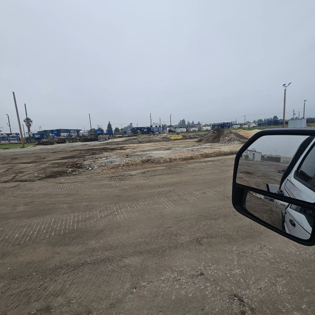 A construction site with dirt ground and equipment in the distance.