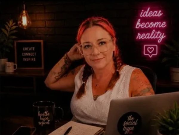 Woman with tattoos and glasses working at a desk.
