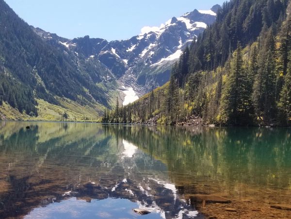 A serene mountain lake reflecting snow-capped peaks and trees.