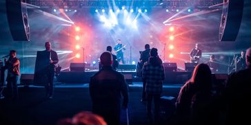 Audience watching a live band perform on a brightly lit stage.