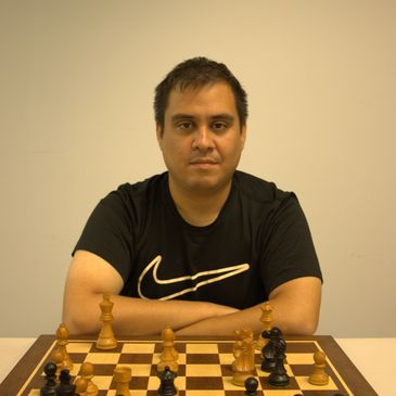 Man sitting at chessboard with serious expression.