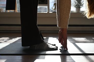 Close up of a forward fold on a black yoga mat