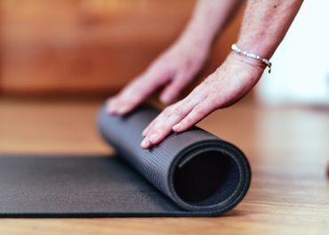 hands rolling out a yoga mat